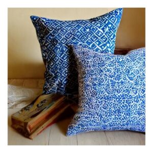A close-up of a handmade block printed cushion cover on a wooden chair.
